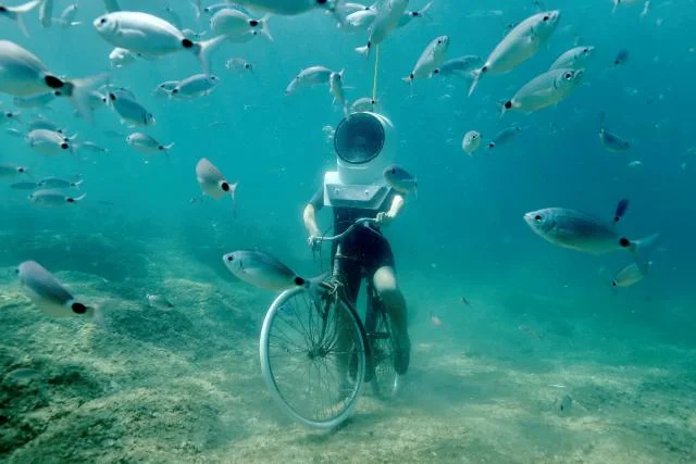 A woman dives and pretends to ride a bike in Underwater Park in Pula