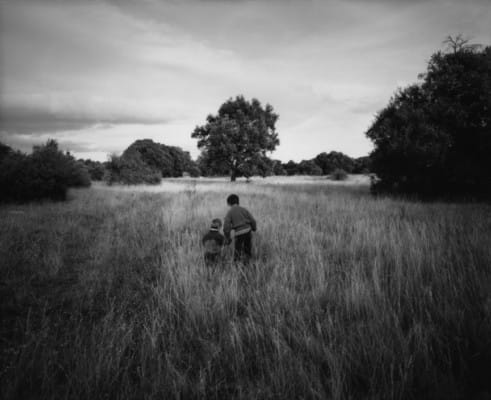 Adulte et enfant dans un champ, photographie de Raymond Depardon