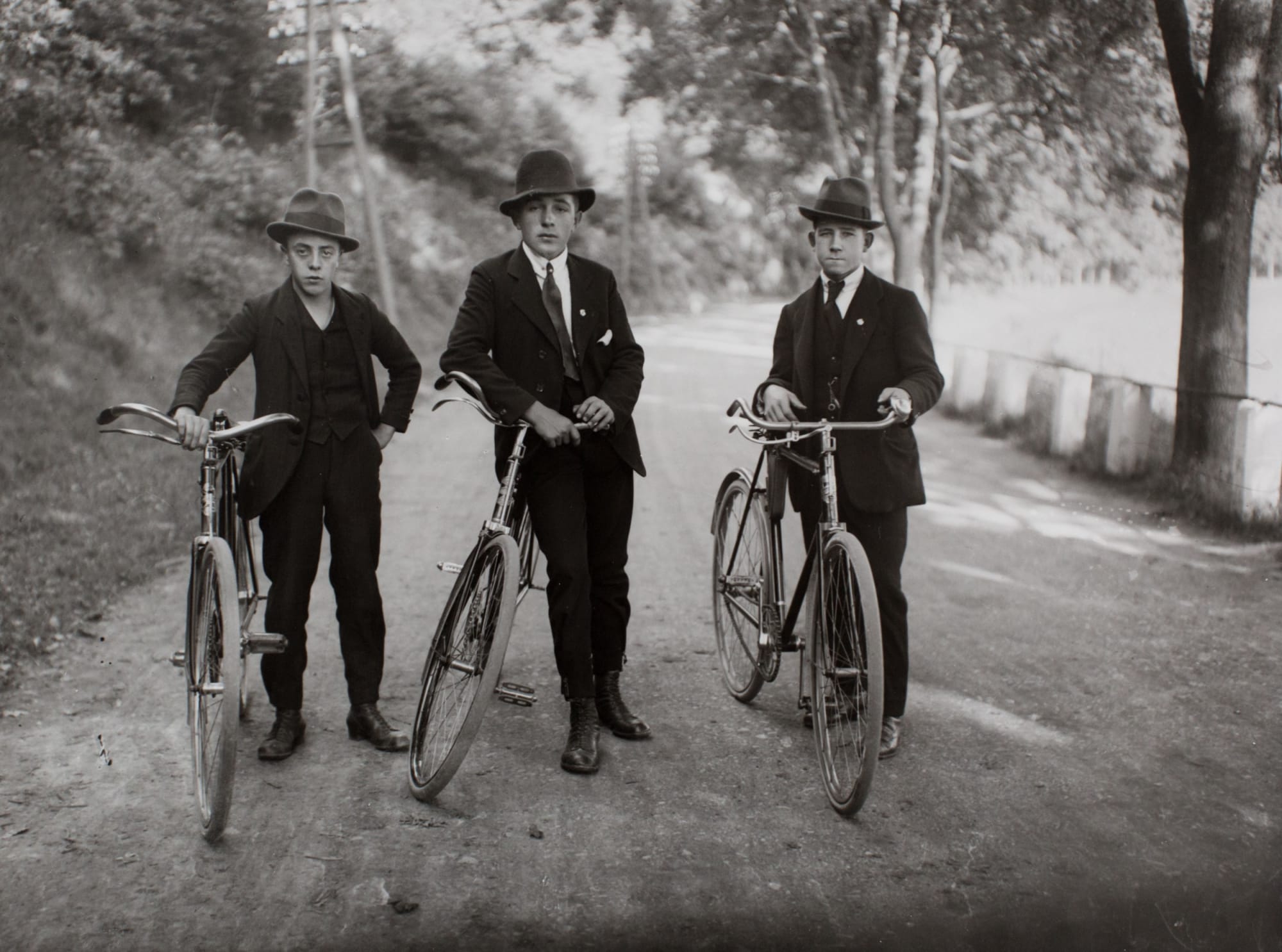 Trois jeunes paysans en costume et chapeau, avec leurs vélos, sur un chemin de campagne, par August Sander