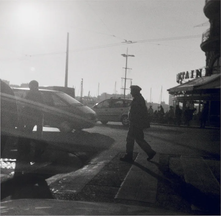 Photographie carrée de Bernard Plossu prise à l'Agfamatic : un homme traverse un quai à contre-jour