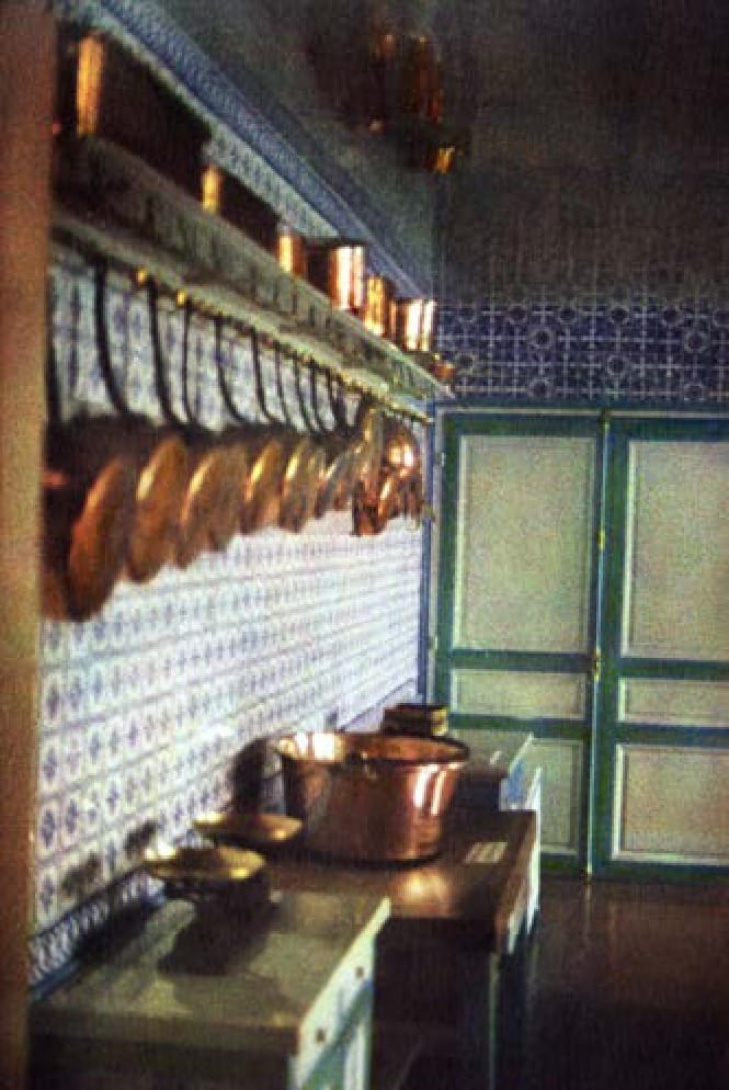 La cuisine de Monet, cuivres alignés au mur et carreaux de faïence bleue