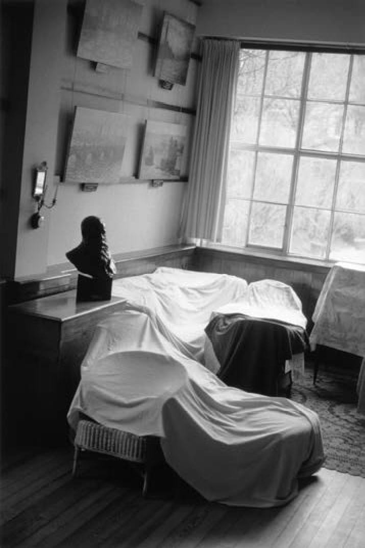 Le salon-atelier de Monet en noir et blanc, meubles sous des housses, tableaux au mur, une fenêtre à droite