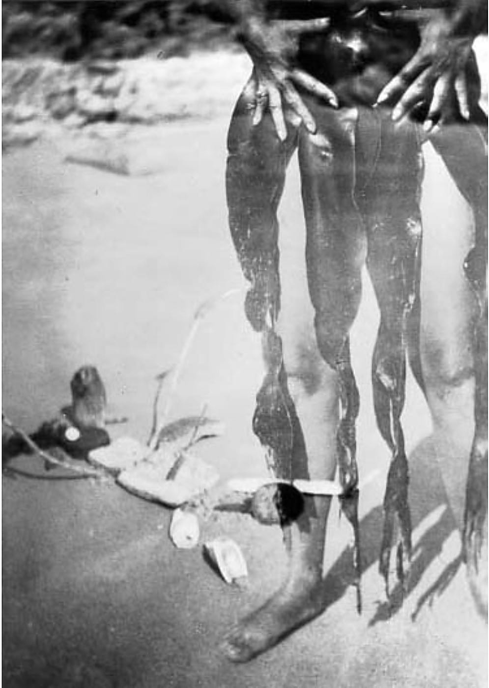 Claude Cahun allongée avec des algues et l'objet intitulé Le Père