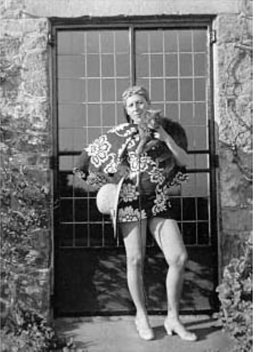 Claude Cahun assise dans l'herbe, un chat sur les genoux