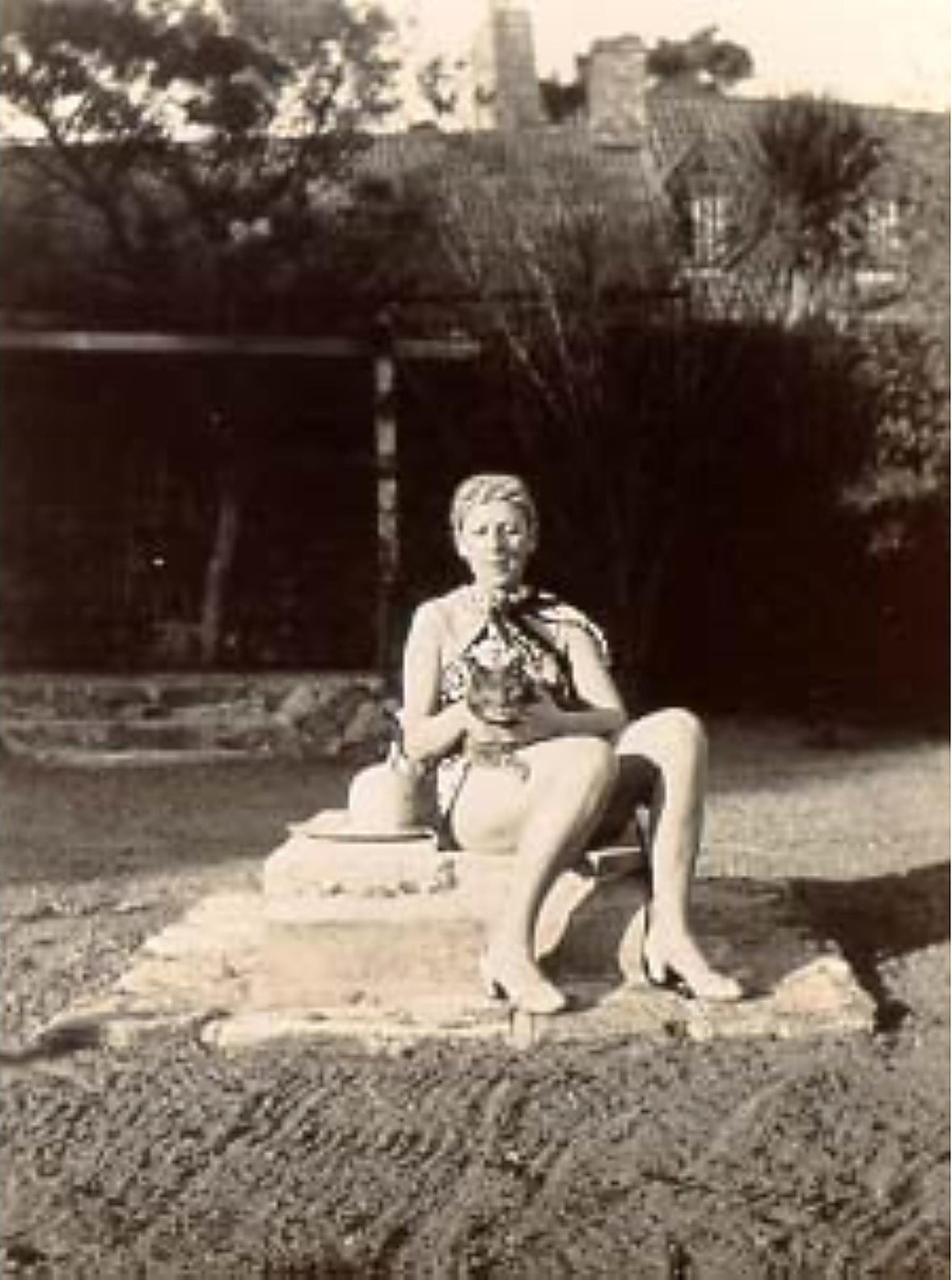 Claude Cahun assise sur un mur, tenant un chat