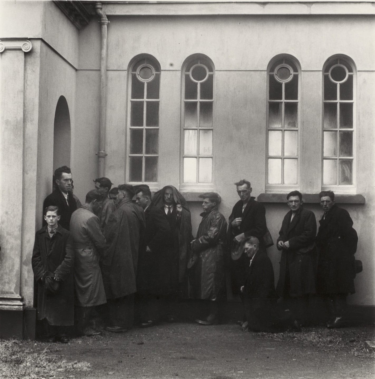 Hommes restés dehors le long du mur de l'église, près d'Inagh, comté de Clare, 1954