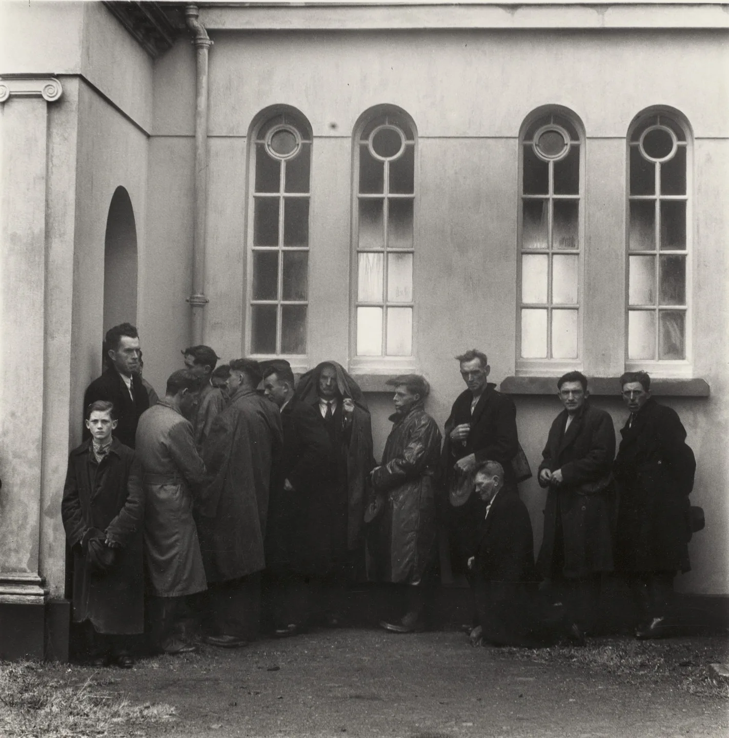 Hommes restés dehors le long du mur de l'église, près d'Inagh, comté de Clare, 1954