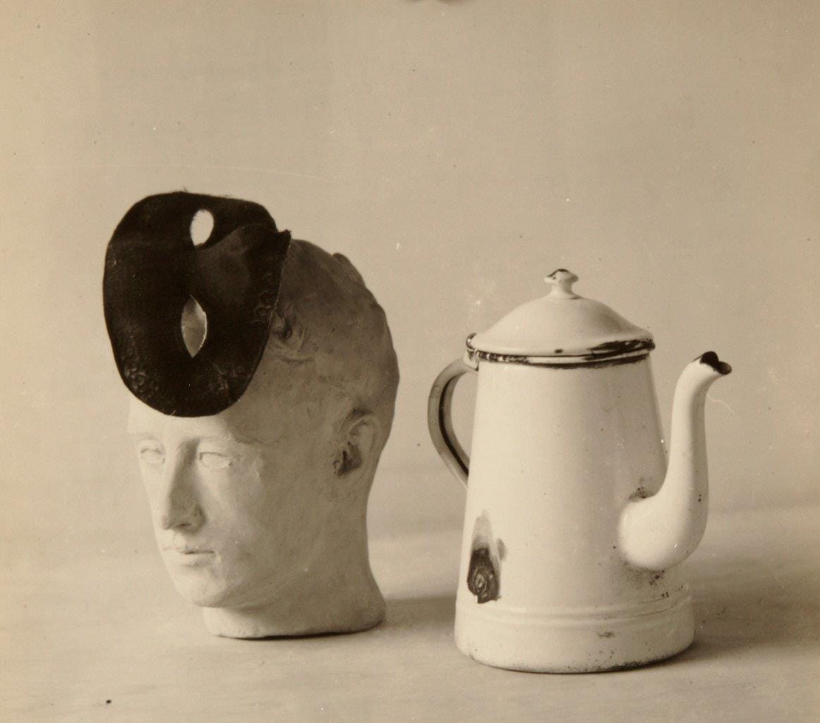Giuseppe Cavalli, nature morte : une tête de plâtre coiffée d'un masque sombre à côté d'une cafetière émaillée