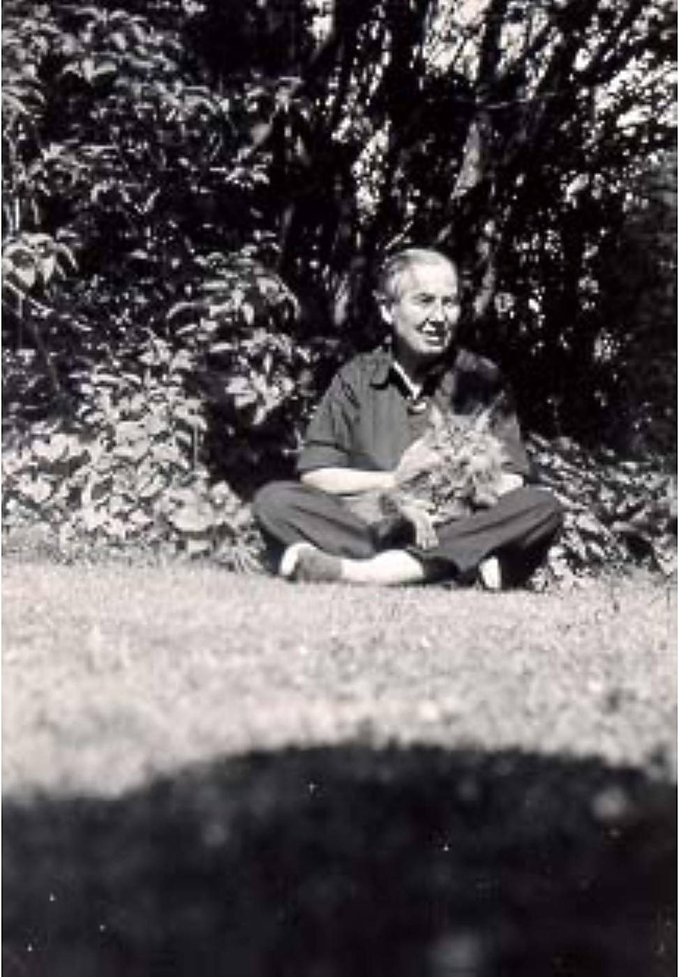 Marcel Moore assise en tailleur dans un jardin, un chat près d'elle