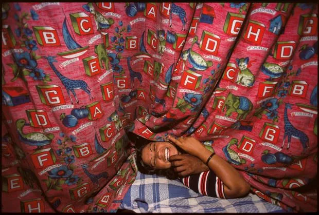 Enfant endormi sous un rideau à lettres, Falkland Road, Bombay, 1978, par Mary Ellen Mark