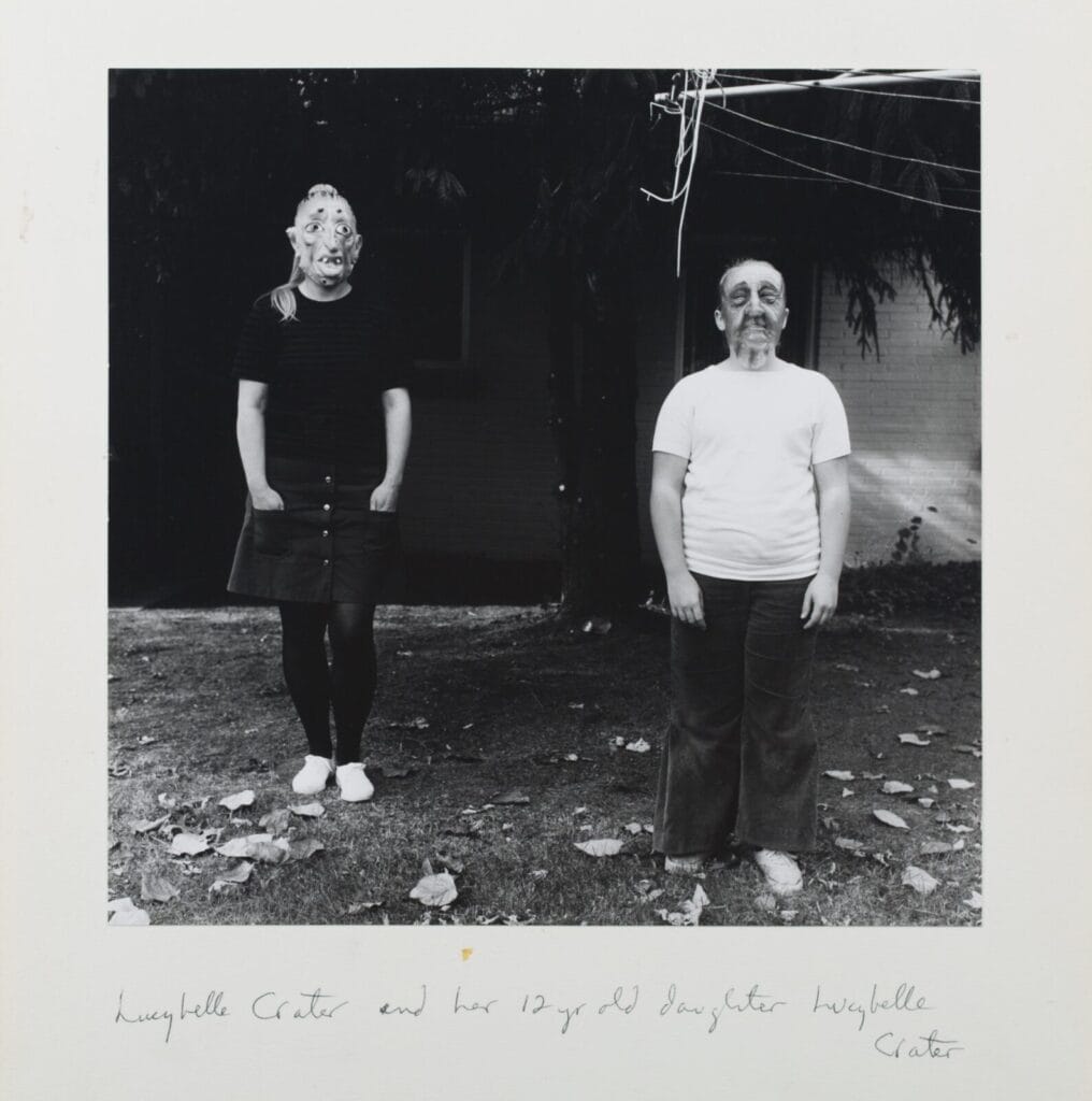 Deux figures debout devant une maison, l'une portant un masque, photographie de Ralph Eugene Meatyard