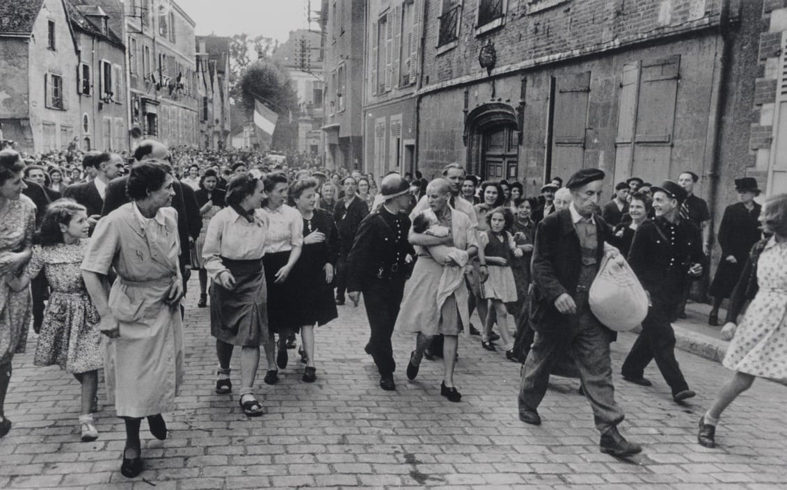 Une femme tondue marche avec son nourrisson dans la foule à Chartres
