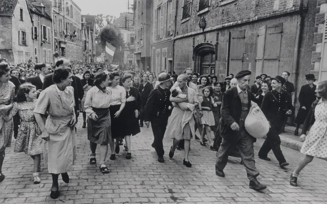 Une femme tondue marche avec son nourrisson dans la foule à Chartres