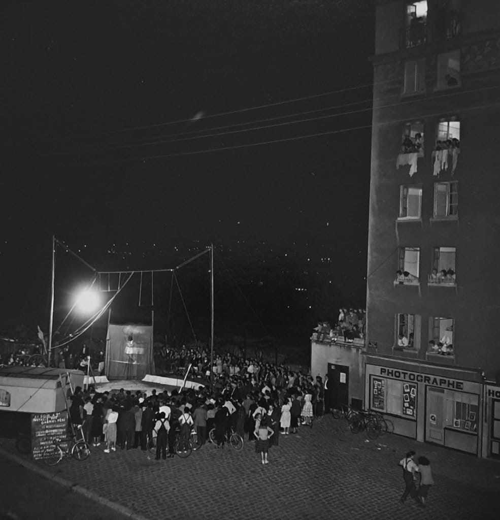 Fête foraine nocturne au pied d'un immeuble de banlieue, Robert Doisneau