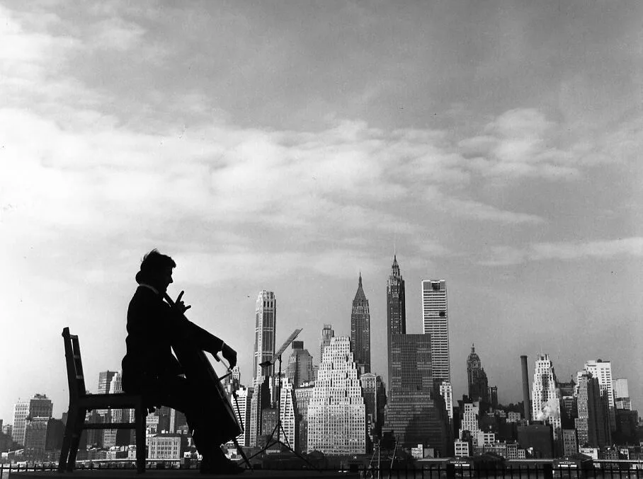 Maurice Baquet joue du violoncelle assis face aux gratte-ciel de Manhattan, Robert Doisneau, 1960