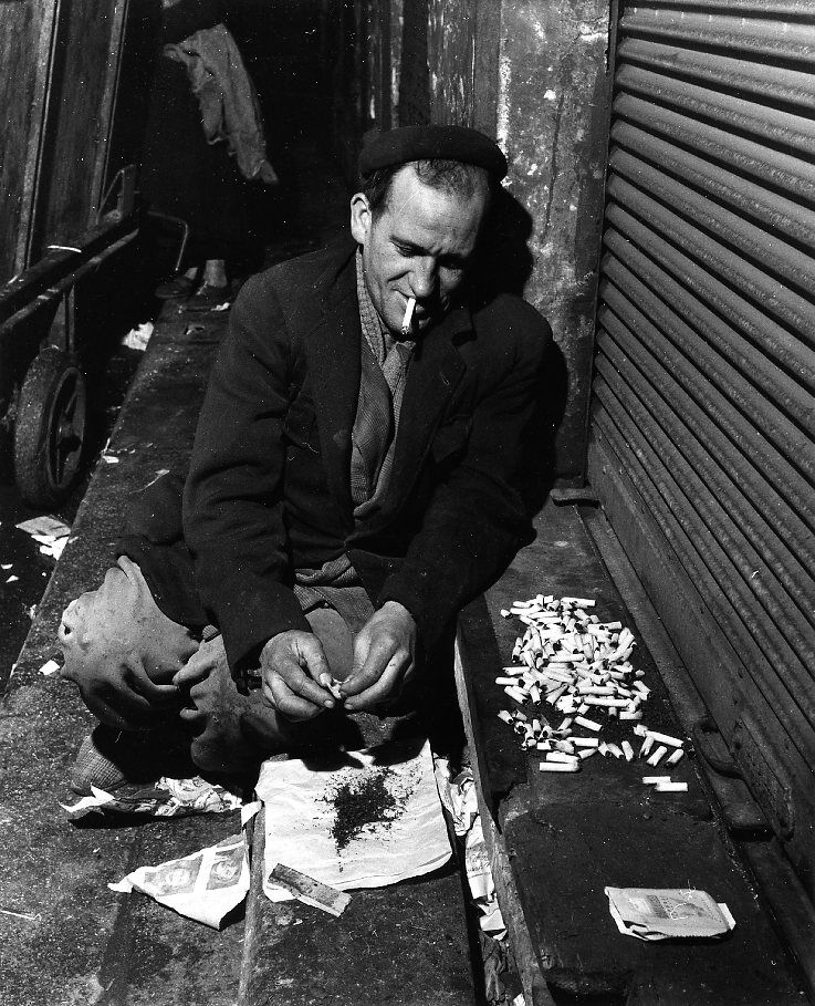 Les mégots, Paris, Robert Doisneau, 1956 : un homme trie des mégots sur un journal