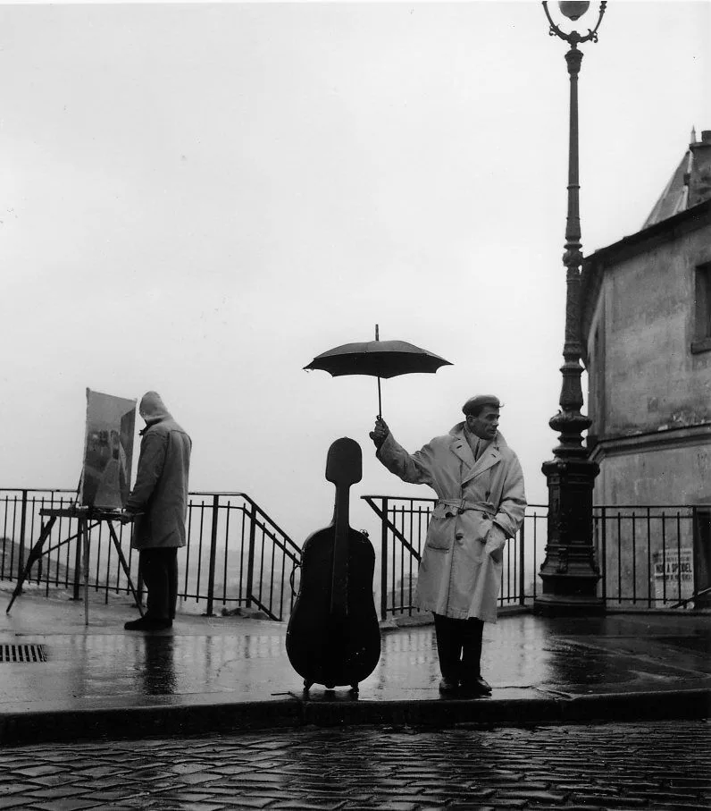 Maurice Baquet tient un parapluie au-dessus de son violoncelle pose sur un quai parisien mouille, 1957