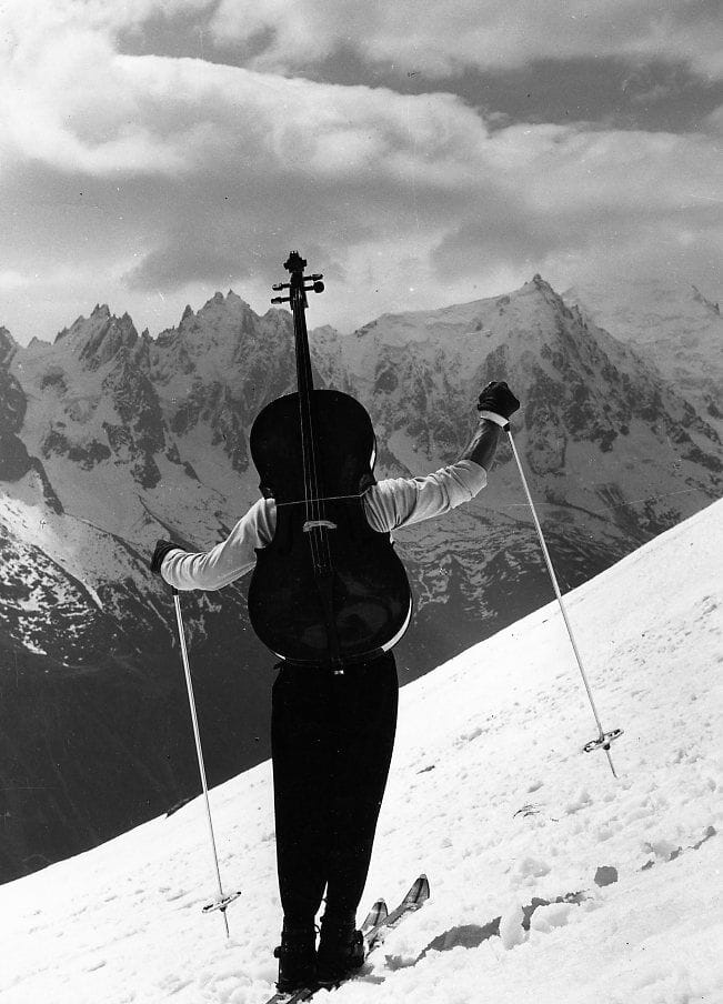 Maurice Baquet a skis, son violoncelle sur le dos, face aux montagnes de Chamonix, photographie par Robert Doisneau en 1957