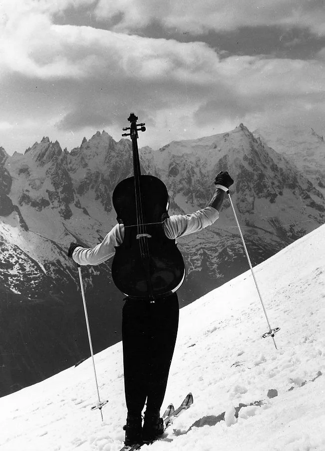 Maurice Baquet a skis, son violoncelle sur le dos, face aux montagnes de Chamonix, photographie par Robert Doisneau en 1957