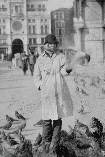 Sophie Calle en manteau clair et chapeau, place Saint-Marc à Venise, entourée de pigeons, 1980